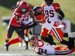 CP-Web.  B.C. Lions' Anthony Thompson, top right, and Branden Dozier, bottom right, tackle Calgary Stampeders' Michael Klukas during first half CFL football action in Calgary, Saturday, June 29, 2019.