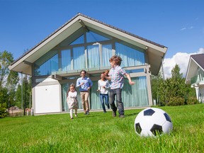 Family with children playing football on the backyard lawn near their house