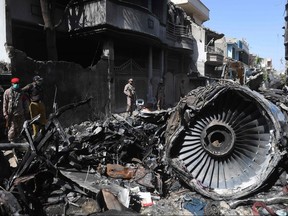 In this file photo taken on May 24, 2020, security personnel stand beside the wreckage of a plane at the site after a Pakistan International Airlines aircraft crashed in a residential area days before, in Karachi.