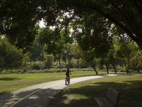 A cyclist rides along a path in Confederation Park during the balmy 21 C temperatures and mostly sunny skies on Friday, August 25, 2017 in Calgary, Alta.