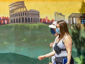 Pedestrians walk in front of a mural in Kensington wearing face masks on Monday, July 20, 2020.
