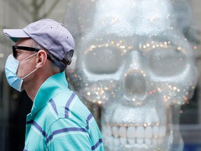 A man wearing a protective face mask, used as a preventive measure against the coronavirus disease (COVID-19), walks past a dummy skull placed in a shop window in central Kyiv, Ukraine July 13, 2020.