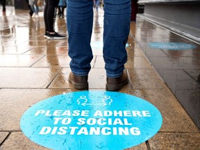 A shopper stands by a pavement sticker asking people to adhere to social distancing measures as they queue to enter a shop on Princes Street in Edinburgh on June 29, 2020 as some non-essential shops reopen as part of Scotland's phased plan to ease out of the coronavirus pandemic lockdown. - Parks, markets and shops with outdoor entrances reopened across Scotland on June 29 marking a further easing of the UK coronavirus lockdown. (Photo by Lesley MARTIN / AFP)