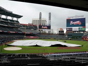 Braves grounds crew members rush to cover the infield as rain interrupted a summer training session at Truist Field in Atlanta, Monday, July 6, 2020.