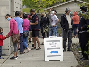 People lined up outside a COVID-19 drop-in testing centre in Edmonton on Wednesday, June 3, 2020. The only testing site in the Edmonton zone is located at Cardinal Collins High School Academic Centre, 7319 29 Ave.