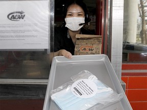 Aiya Hernia at A&W on Macleod Trail in the S.E. poses for a photo as Alberta will distribute 20 million free face masks to residents.