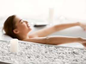 Enjoy Spa Procedure. Woman Lying In Bath With Foam And Candles