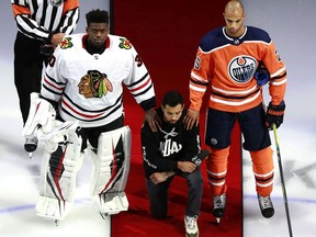 EDMONTON, ALBERTA - AUGUST 01: Malcolm Subban #30 of the Chicago Blackhawks and Darnell Nurse #25 of the Edmonton Oilers place their hands on Mathew Dumba of the Minnesota Wild during the national anthem of the United States before the Game One of the Eastern Conference Qualification Round prior to the 2020 NHL Stanley Cup Playoffs  at Rogers Place on August 01, 2020 in Edmonton, Alberta.Dumba spoke before the game about the NHL's support of Black Lives Matter and ending racism.
