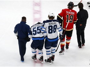 EDMONTON, ALBERTA - AUGUST 01: Mark Scheifele #55 of the Winnipeg Jets is helped off of the ice by Nathan Beaulieu #88 of the Winnipeg Jets after a hard hit against the Calgary Flames in Game One of the Western Conference Qualification Round prior to the 2020 NHL Stanley Cup Playoffs at Rogers Place on August 01, 2020 in Edmonton, Alberta. (Photo by Jeff Vinnick/Getty Images)