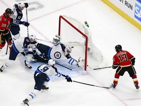 Johnny Gaudreau #13 of the Calgary Flames scores a goal as Connor Hellebuyck #37 of the Winnipeg Jets dives to defend in Game One of the Western Conference Qualification Round prior to the 2020 NHL Stanley Cup Playoffs at Rogers Place on August 01, 2020 in Edmonton, Alberta.