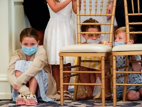 Children who had not been wearing protective face masks wear masks just provided to them by the White House because of the coronavirus (COVID-19) pandemic as they wait to watch U.S. President Donald Trump hold a news conference at his golf resort in Bedminster, N.J., August 7, 2020.