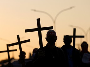 People hold crosses as they attend a tribute to the 100,000 victims of the coronavirus disease and a protest against Brazil's President Jair Bolsonaro, in Sao Paulo, Brazil, Aug. 7, 2020.