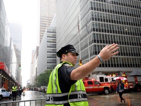 A policeman gestures near fire trucks after a helicopter crash-landed on top of a building in midtown Manhattan in New York. JOHANNES EISELE/AFP/Getty Images