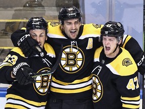 Patrice Bergeron (37) of the Boston Bruins celebrates with Brad Marchand (63) and Torey Krug (47) after scoring the winner against the Carolina Hurricanes at Scotiabank Arena on August 12, 2020 in Toronto.