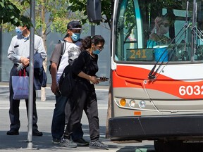 Transit passengers wear masks as they board a Calgary Transit bus in downtown Calgary on Thursday, August 6, 2020.