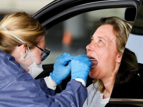 A member of medical staff takes coronavirus test samples of a woman during drive-thru COVID-19 testing, on a converted ice rink, in Alkmaar, Netherlands, April 8, 2020.