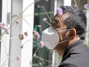 Ngawang Kherab is seen cleaning the windows on the TELUS Convention Centre while wearing a mask along Stephen Ave. SW on Monday, August 10, 2020.
