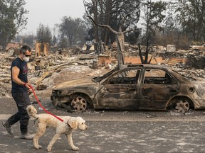 Jerod Knox walks his dog, Bear, through his neighbourhood after searching for belongings in his destroyed house on Sept. 15, 2020 in Talent, Oregon.