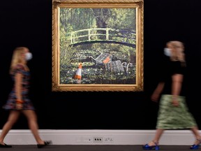 Employees wearing face masks or coverings due to the COVID-19 pandemic, pose with artwork entitled "Show me the Monet" by the artist Banksy, during a photocall at Sotheby's auction house in London, on Sept. 18, 2020, ahead of the forthcoming 'Modernites/Contemporary' evening auction set to take place in October.