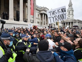 Police move in to disperse protesters in Trafalgar Square in London on Sept. 26, 2020, at a 'We Do Not Consent!' mass rally against vaccination and government restrictions designed to fight the spread of the novel coronavirus, including the wearing of masks and taking tests for the virus.
