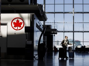 A passenger wheels her luggage near an Air Canada logo at Toronto Pearson International Airport on April 1, 2020. (Photo by Cole Burston/Getty Images)