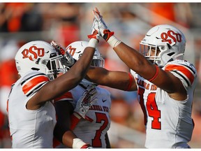 STILLWATER, OK - SEPTEMBER 26:  Linebacker Calvin Bundage #1 gets congratulated by linebacker Amen Ogbongbemiga #7 and defensive end Trace Ford #94 of the Oklahoma State Cowboys after sacking quarterback Jarret Doege of the West Virginia Mountaineers for a loss of six yards in the third quarter on September 26, 2020 at Boone Pickens Stadium in Stillwater, Oklahoma.