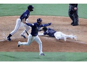 Randy Arozarena of the Tampa Bay Rays slides into home plate during the ninth inning to give his team  an 8-7 victory, as Kevin Kiermaier celebrates, against the Los Angeles Dodgers in Game 4 of the World Series at Globe Life Field in Arlington, Texas, on Oct. 24, 2020.