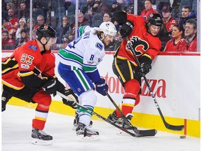CALGARY, AB - NOVEMBER 11: Mark Jankowski #77 of the Calgary Flames fights Chris Tanev #8 of the Vancouver Canucks for the puck during an NHL game at Scotiabank Saddledome on November 11, 2017 in Calgary, Alberta, Canada.