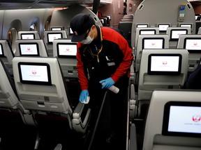 A staff member of Japan Airlines wearing a protective face mask and gloves cleans the cabin of a plane after a domestic flight at Haneda airport in Tokyo, Japan May 26, 2020.