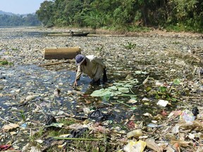 A scavenger collects plastic waste for recycling on the Citarum river choked with garbage and industrial waste, in Bandung, West Java. GETTY IMAGES