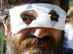 A protestor wears a face mask over his eyes with holes cut out during a demonstration against the government's coronavirus restrictions, in Konstanz, Germany Sunday, Oct. 4, 2020.