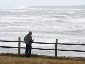 A man watches waves crash into the shore after the arrival of Tropical Storm Teddy at Point Michaud on Cape Breton, Nova Scotia, Sept. 23, 2020.