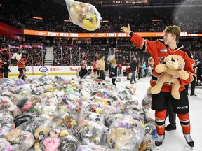 The Calgary Hitmen’s Carson Focht helps gather up teddy bears after scoring during the Teddy Bear Toss game against Red Deer Rebels at the Saddledome on Sunday, Dec. 1, 2019.