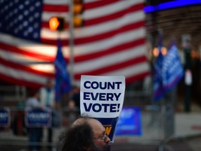 A man holds a placard that reads "Count Every Vote" while demonstrating across the street from supporters of President Donald Trump outside of where votes are still being counted in Pennsylvania, six days after the general election on Nov. 9, 2020.