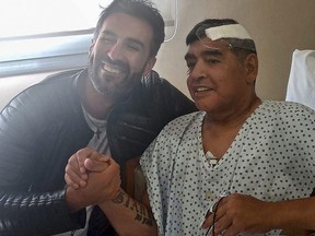 This handout photo taken Nov. 11, 2020 and released by the press officer of Diego Armando Maradona shows Argentine soccer legend Diego Maradona (right) shaking hands with his doctor Leopoldo Luque in Olivos, Argentina.