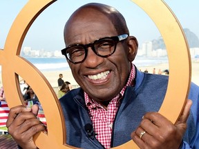 Al Roker pose for a photo through Olympic rings on the Today show set on Copacabana Beach on August 13, 2016 in Rio de Janeiro, Brazil.