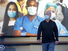 Kelly Young walks past a billboard along Macleod Trail in Calgary as COVID cases increase on Tuesday, November 17, 2020.