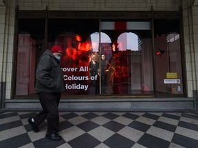 A masked pedestrian walks in front of a window shop decorated for the holiday season in downtown Calgary on Friday, December 11, 2020.