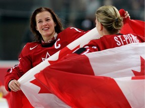 Cassie Campbell and Kim St-Pierre hold Canadian flags and celebrate their 4-1 victory over Sweden to win the gold medal at the 2006 Olympic Games in Torino.