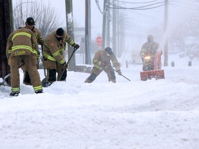 Firefighters clear the sidewalk around station 4 after a winter storm hit the city on Tuesday, Dec. 22, 2020.