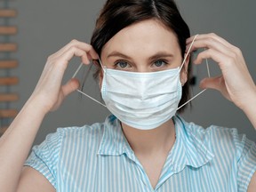 A woman puts on a surgical mask in this file photo.