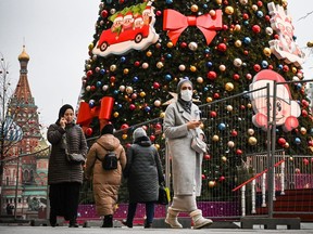 People walk along the Red Square in central Moscow past Christmas decorations wearing protective masks, amid the crisis linked to the COVID-19 pandemic on Nov. 27, 2020.