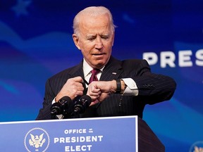 President-elect Joe Biden looks at his watch during a news conference at Biden's transition headquarters in Wilmington, Delaware, December 16, 2020.