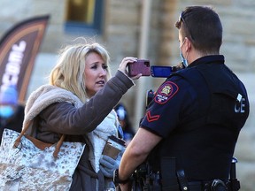 A protester and a Calgary police officer record each other during a downtown rally against pandemic restrictions on Sunday, Dec. 20, 2020.