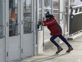 A person is seen trying to close the door against the strong wind at Crowfoot LRT Station on Wednesday, Jan. 13, 2021.
