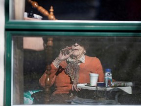 A resident waves from her room, inside a seniors' long-term care facility, following a number of deaths since the COVID-19 outbreak, in the suburb of Dorval in Montreal, April 11, 2020.