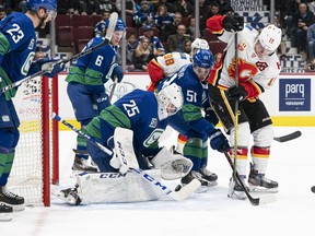 The Calgary Flames’ Matthew Tkachuk tries to put a backhand shot past Vancouver Canucks goalie Jacob Markstrom at Rogers Arena in Vancouver on Feb. 8, 2020 in Vancouver. Canucks Alexander Edler (23) and Troy Stecher (51) help defend on the play.