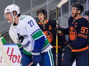 EDMONTON, AB - JANUARY 14: Connor McDavid #97 of the Edmonton Oilers celebrate his hat trick against the Vancouver Canucks as Travis Hamonic #27 skates off at Rogers Place on January 14, 2021 in Edmonton, Canada.