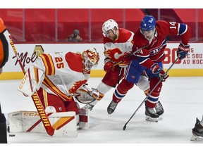Calgary Flames goaltender Jacob Markstrom makes a pad save near teammate Nikita Nesterov and the Montreal Canadiens’ Nick Suzuki at the Bell Centre in Montreal on Jan. 30, 2021.