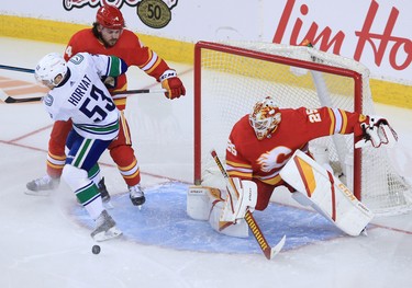 Calgary Flames goaltender Jacob Markstrom watches the puck as Vancouver Canucks forward Bo Horvat and Flames defensemen Ramus Andersson wrestle during the Calgary Flames NHL home opener on Saturday, January 16, 2021. 
Gavin Young/Postmedia